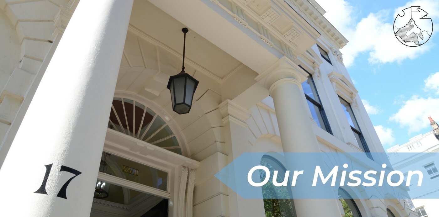 Our Mission desktop Image of the front entrance of the GHIL, taken from a low angle and showing the building from the left of the portico to the upper right corner of the building, highlighting the number 17 on the left-hand pillar of the portico. In the top right corner is GHIL mission symbol of a mountain with a flag on the top, inside a circle, and on a blue arrow shape running horizontally across the picture from the right-hand side to the middle are the words "Our Mission".