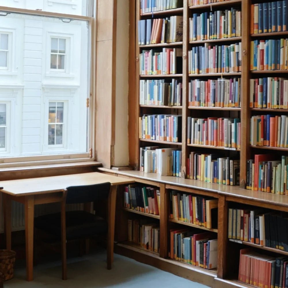 A desk and chair in front of a window surrounded by shelves with books.